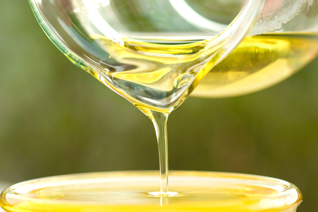 Óleo de algodão sendo despejado em recipiente, mostrando sua textura e uso culinário
