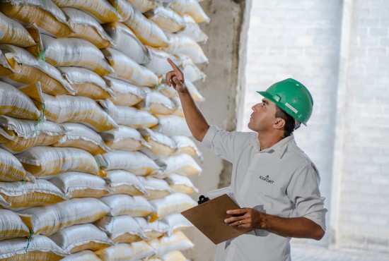 Profissional verificando estoque de sacos de torta de algodão em armazém para distribuição